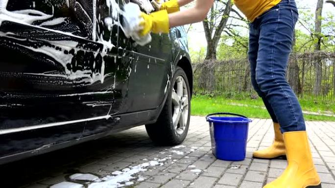 女人在露天洗汽车。手持镜头。