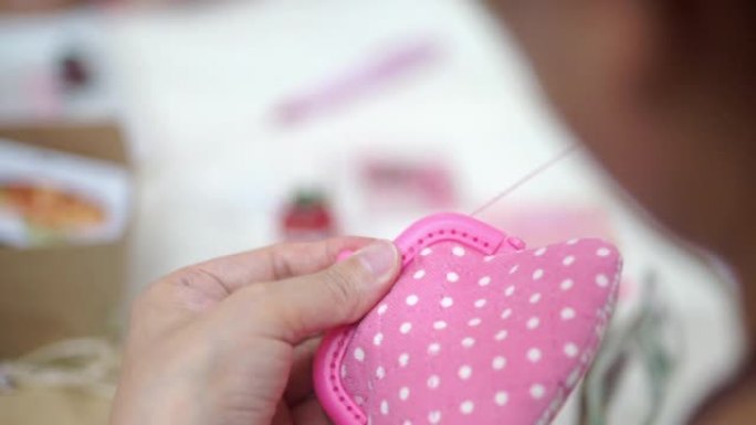 用针用手缝制织物，制成粉红色口袋。