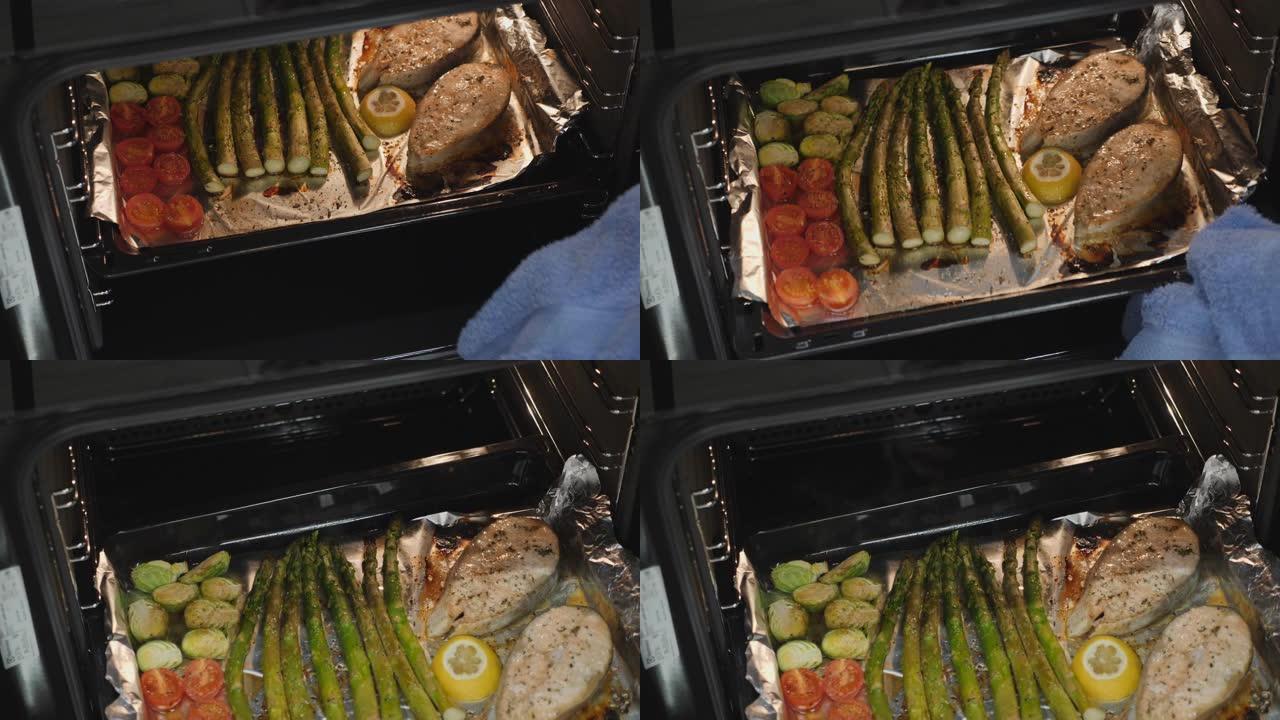 烤箱烤鱼牛排和蔬菜。女人煮了美味的鲑鱼。在家庭厨房准备蔬菜。健康饮食。烤盘上的烘焙食品