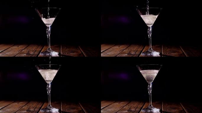 马提尼酒被倒入木制表面上的玻璃杯中的特写镜头。