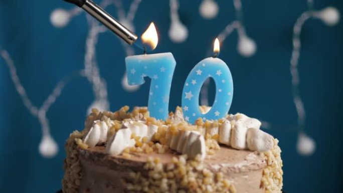 蓝色背景上有70号蜡烛的生日蛋糕。蜡烛着火了。慢动作和特写视图
