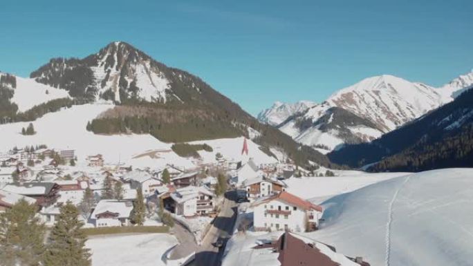 航拍奥地利伯旺的冬季，滑雪村，明亮的阳光照射在斜坡上