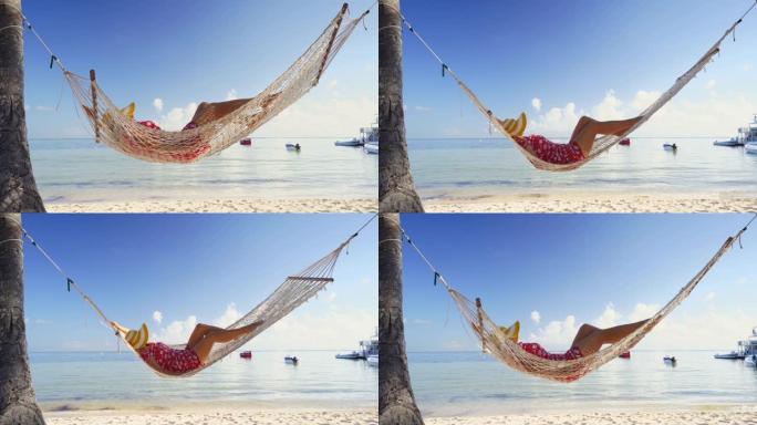 女孩在热带岛屿海滩的吊床上放松。多米尼加共和国蓬塔卡纳的暑假