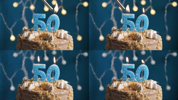 蓝色背景上有50号蜡烛的生日蛋糕。蜡烛着火了。慢动作和特写视图