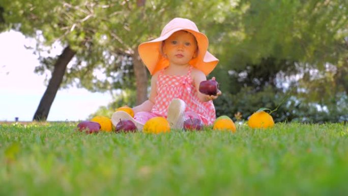 小公主在户外玩水果。巴拿马的孩子在后院户外玩得开心。快乐的童年概念。蹒跚学步的孩子坐在绿草地上等待母