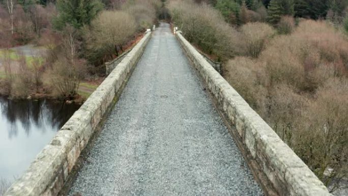 在阴暗的春季，在森林旁边的苏格兰河上的一座废旧铁路桥的鸟瞰图