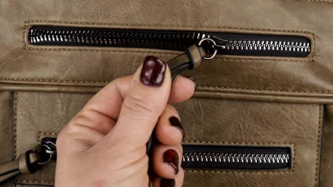 用拉链将锁合上，一个棕色女式包的口袋。特写。
