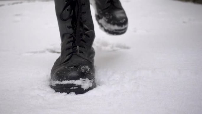 穿着沉重靴子的男子在白雪皑皑的地面上有力地踩着脚步