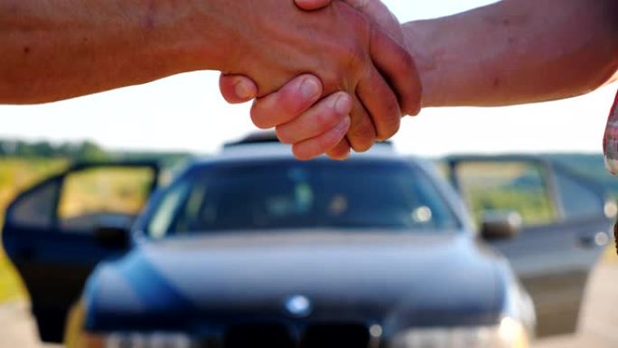 交易成功后，推销员与汽车新主人握手。卖方祝贺买方购买。室外摇晃男性手臂。慢动作特写