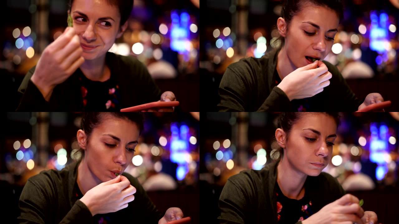 美女在餐厅看手机时吃豌豆，面带微笑