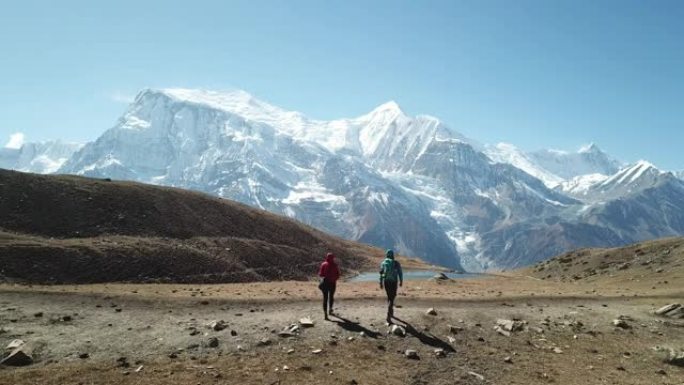 夫妇徒步前往尼泊尔喜马拉雅山安纳普尔纳巡回赛的一部分冰湖。他们很高兴。安纳普尔纳链在后面，被雪覆盖。