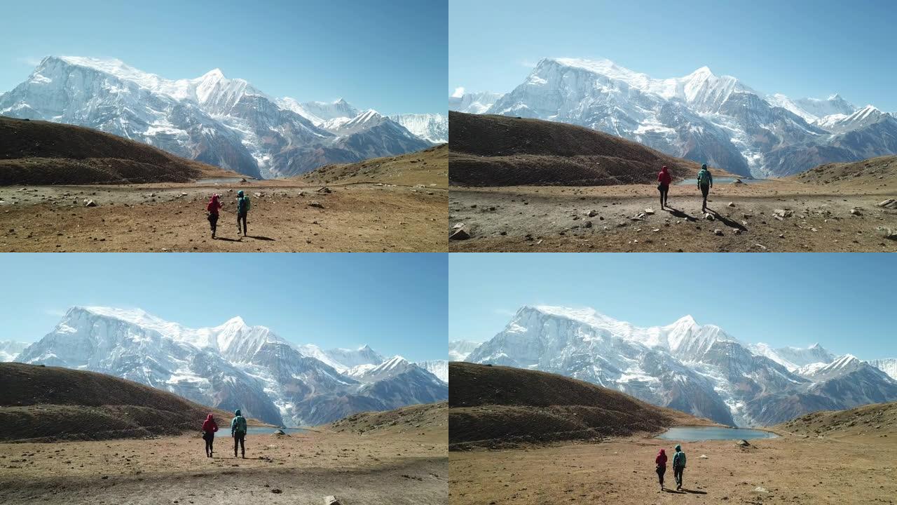 夫妇徒步前往尼泊尔喜马拉雅山安纳普尔纳巡回赛的一部分冰湖。他们很高兴。安纳普尔纳链在后面，被雪覆盖。
