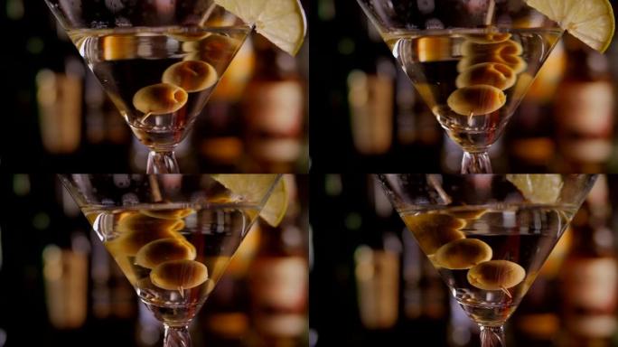 马提尼酒杯的特写镜头，橄榄在酒瓶上缓慢旋转。