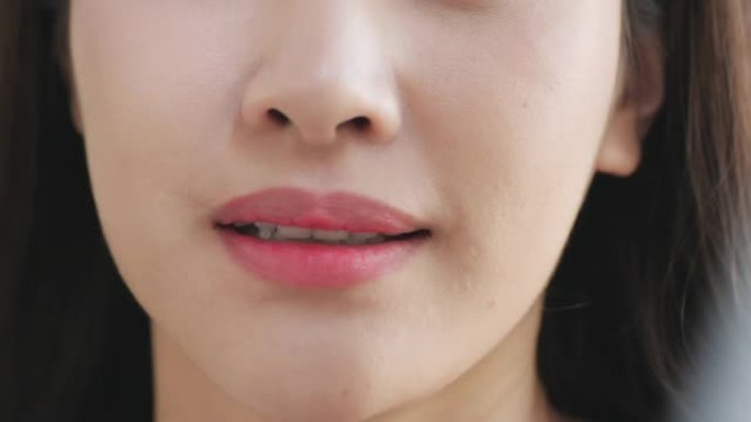 慢动作: 微笑的女人咬着光滑的嘴唇的特写镜头