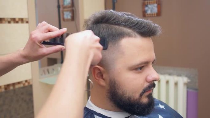 男性在理发沙龙，近距离拍摄。用理发推子和梳子给客户理发。理发店内部。