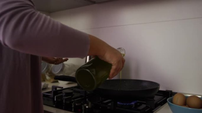 女人将油倒入锅中并将鸡蛋打入锅中