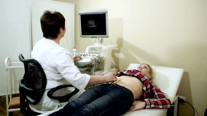 医生用超声波扫描仪检查女性腹部器官。高清