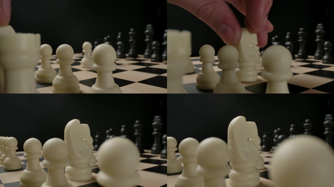 人的手从第一线移动象棋人物骑士。小型塑料象棋的宏观射击