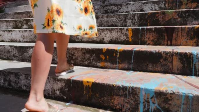 美丽苗条的女性腿在夏季凉鞋爬楼梯。晒黑的女性腿的特写侧视图