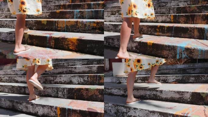 美丽苗条的女性腿在夏季凉鞋爬楼梯。晒黑的女性腿的特写侧视图