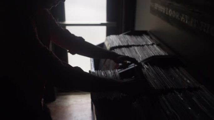 一个男人在唱片店里筛选一盒黑胶唱片的剪影