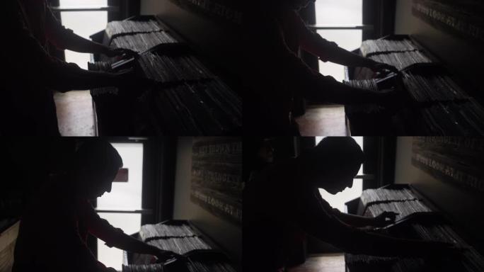一个男人在唱片店里筛选一盒黑胶唱片的剪影