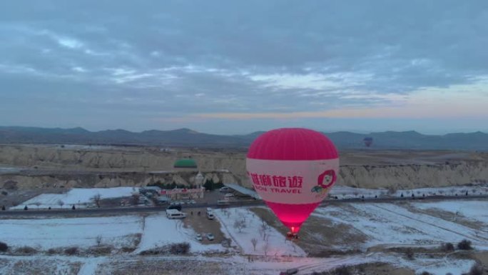 独自热气球在土耳其卡帕多细亚的白雪皑皑的风景下低飞