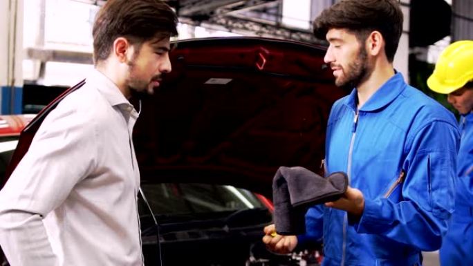 男子专家汽车维修部门的汽车修理工与客户一起检查发动机油位。4k电影镜头。