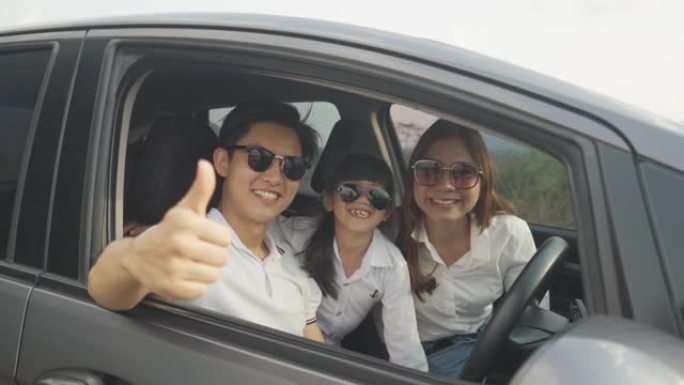 快乐的亚洲家庭，父亲竖起大拇指，母女俩在紧凑型汽车上戴着太阳镜，微笑着开车去度假。汽车保险或租赁和家