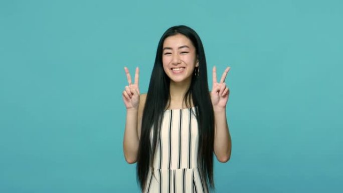 乐观的亚洲女性，长长的直发，显示双v形标志，胜利或和平手势