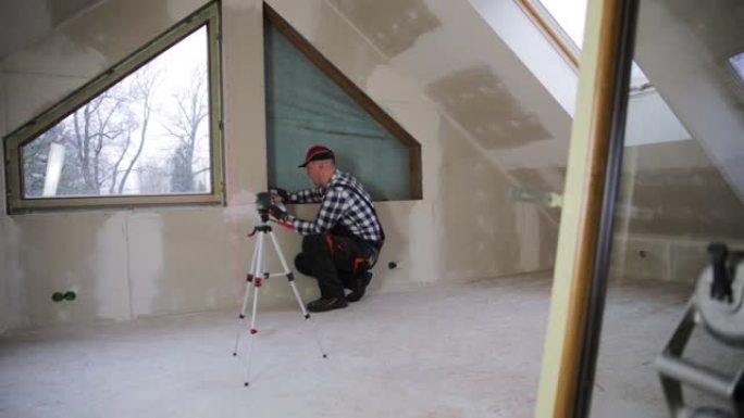 杂工，建筑工人在新的隔热和填充的干墙阁楼中安装PVC窗户。