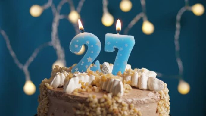 蓝色背景上有27个数字蜡烛的生日蛋糕。蜡烛吹灭了。慢动作和特写视图