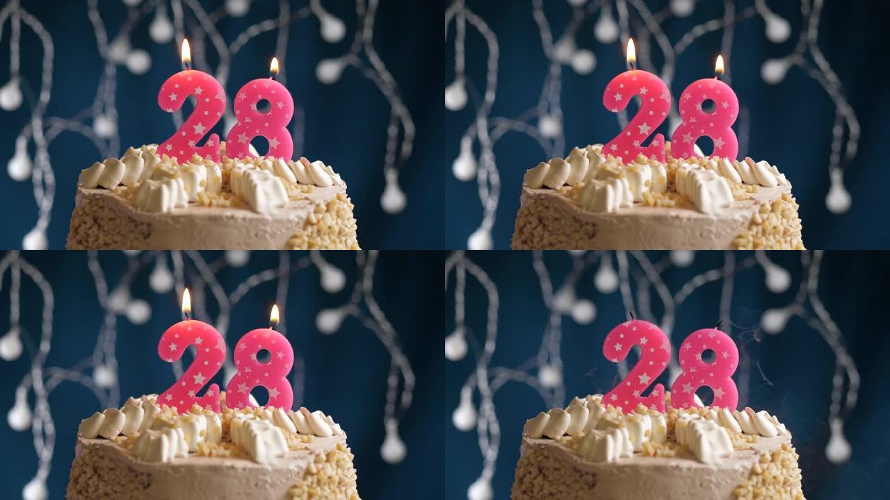 蓝色背景上有28号粉色蜡烛的生日蛋糕。蜡烛吹灭了。慢动作和特写视图