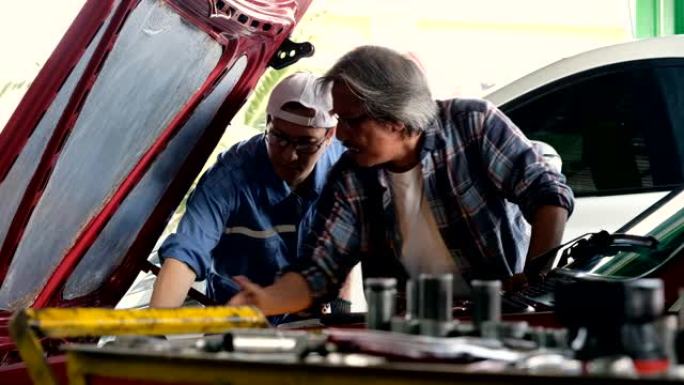 汽车修理工与老顾客谈论车库的发动机维修。