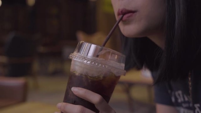 4k年轻的亚洲成年女性坐在吸管上喝一杯咖啡。空闲时间，白天冷，美式咖啡，咖啡馆压力大，咖啡因，体贴，