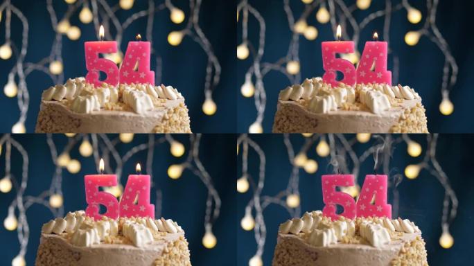 蓝色背景上有54号粉色蜡烛的生日蛋糕。蜡烛吹灭了。慢动作和特写视图