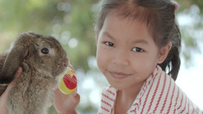 亚洲小女孩和小兔子一起拿着复活节彩蛋