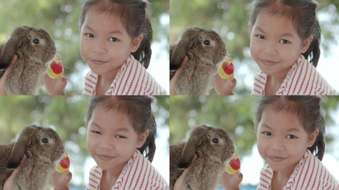 亚洲小女孩和小兔子一起拿着复活节彩蛋