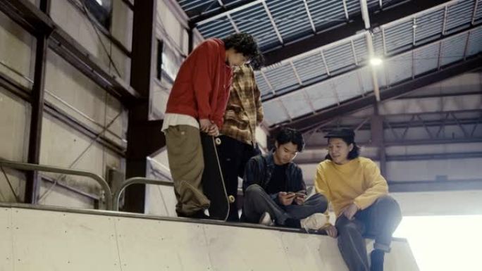 一群日本男孩在滑板公园使用智能手机