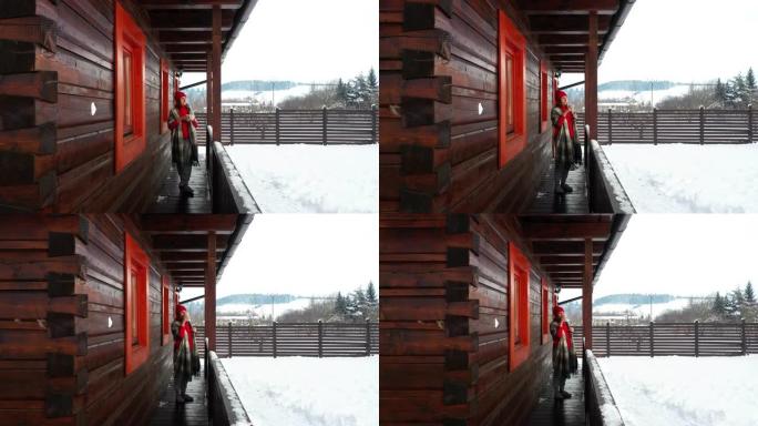 4k女人冬天穿着红色豆豆在木制避暑别墅的露台上喝茶
