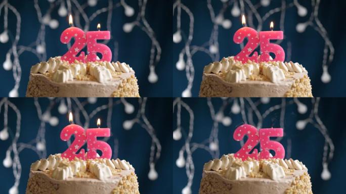 蓝色背景上有25号粉色蜡烛的生日蛋糕。蜡烛吹灭了。慢动作和特写视图