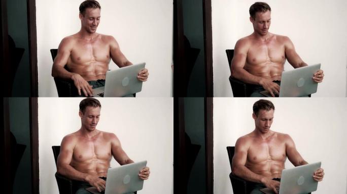 赤裸上身的男人与性感的身体坐在椅子上与笔记本电脑，谈论网络摄像头，笑