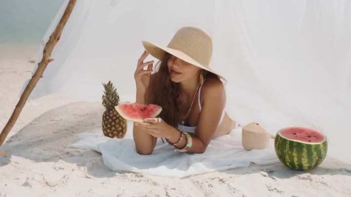 在热带海滩上吃西瓜的女人