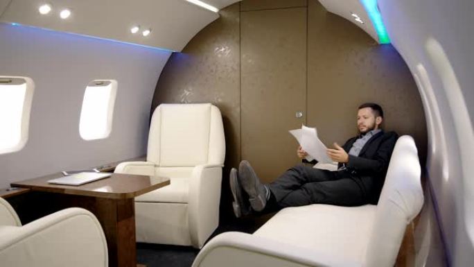 企业主首席银行家董事正在飞机的皮沙发上看合同