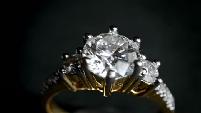 钻石戒指的极端细节在黑暗背景上旋转时特写镜头