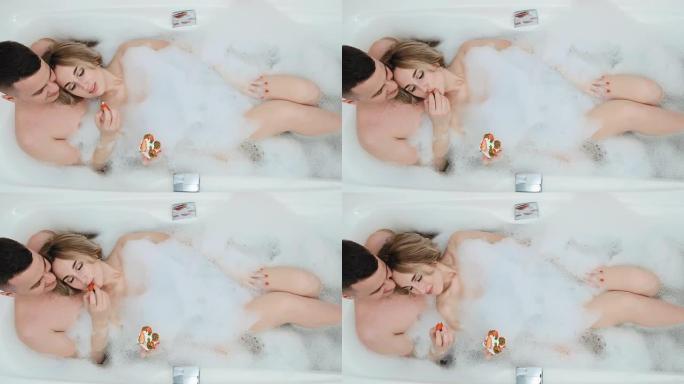 这对夫妇躺在浴缸里，浴缸里有泡沫和奶油草莓