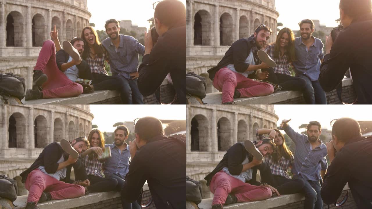 日落时坐在罗马斗兽场前的四个年轻朋友游客用背包太阳镜拍照快乐美丽的女孩长发