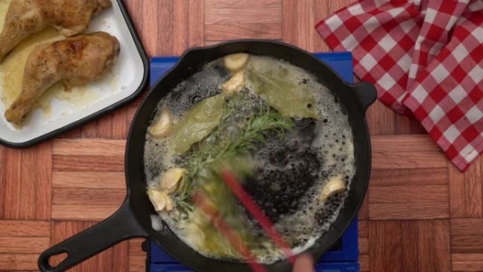 厨师搅拌融化的黄油，烤大蒜，百里香，月桂叶，顶视图的混合物