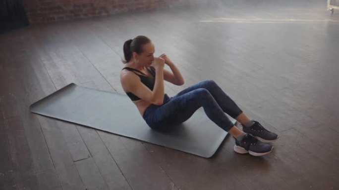 运动垫上的女运动员在健身房做仰卧起坐。肌肉发达的女运动员做腹肌锻炼
