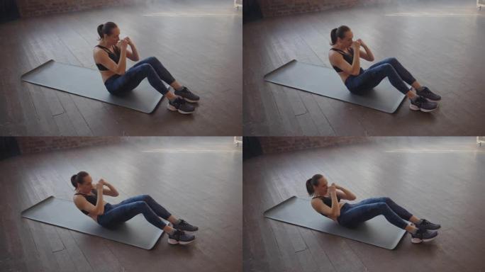 运动垫上的女运动员在健身房做仰卧起坐。肌肉发达的女运动员做腹肌锻炼